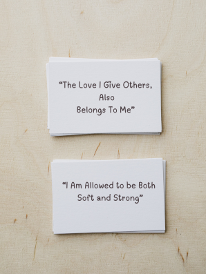 Soft notecards with uplifting messages scattered on a cozy surface, offering warm, encouraging reminders for caregivers who need emotional support.