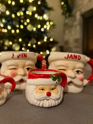 Three Santa mugs arranged together with a softly lit Christmas tree in the background, symbolizing a cherished family holiday tradition.