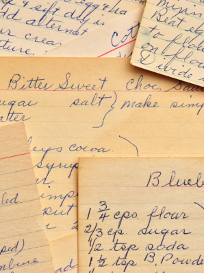 Close-up of vintage handwritten recipe cards with ingredient lists and notes, symbolizing family traditions, love, and preserved culinary legacy.
