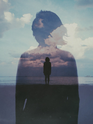 A layered silhouette of a woman standing alone on a shoreline, with clouds and sky blended into her outline, symbolizing reflection, identity, and the quiet space between roles.